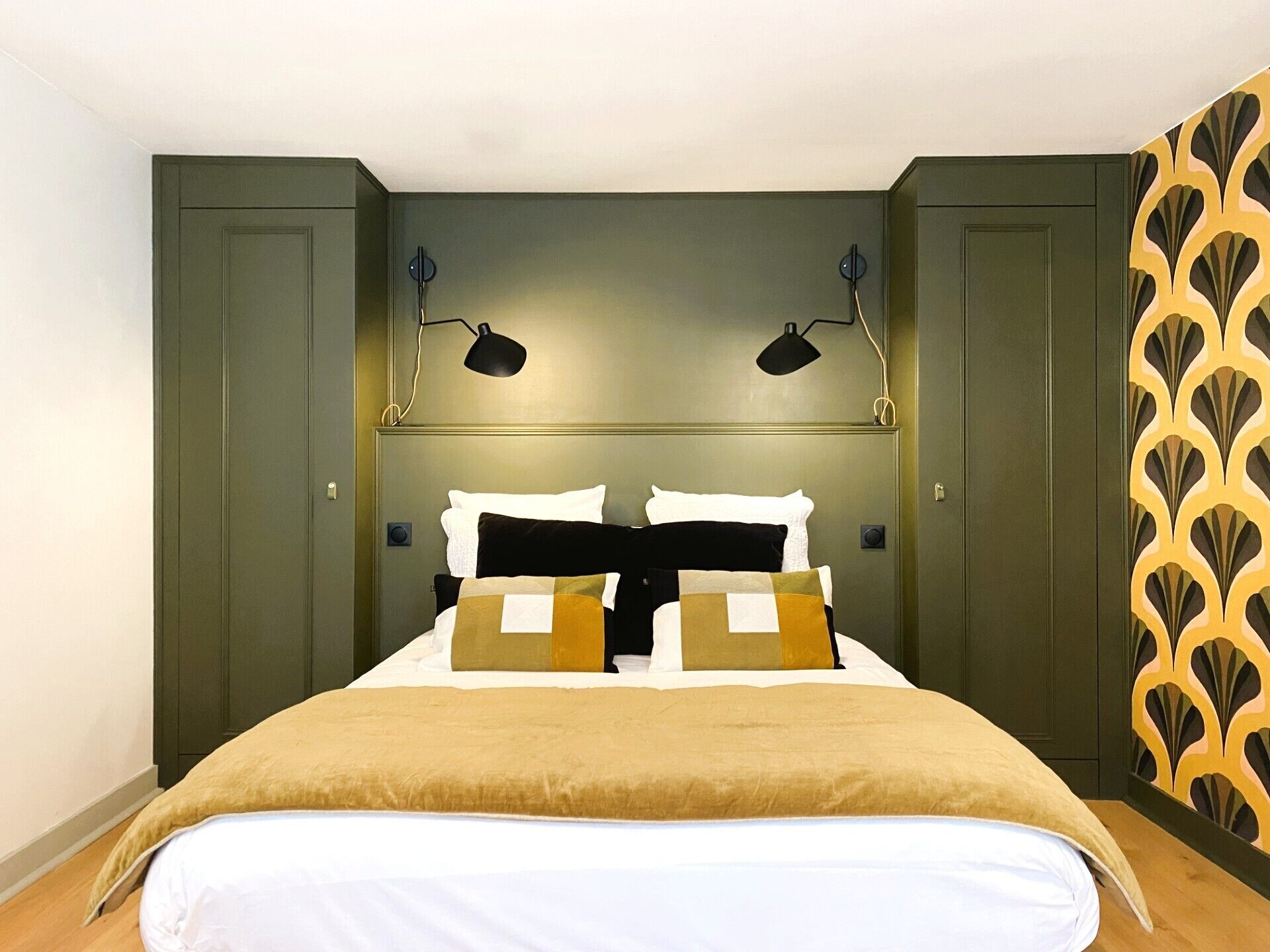 Un dormitorio con una cama, dos lámparas de noche y un papel tapiz estampado.