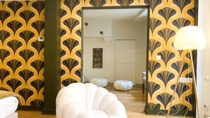 Una sala de estar moderna con una silla blanca escultural, una lámpara de pie y un diseño de papel tapiz estampado.