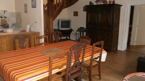 Een eetgedeelte met een houten tafel en stoelen, een televisie en een kast.