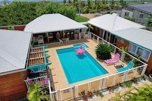 Une piscine agrémentée d’un flotteur en forme de flamant rose, entourée de chaises longues et d’un patio couvert.