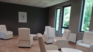 A room with multiple white leather chairs and a small white table, large windows with a view of greenery, and a tiled floor. - Gites de Mon Clocher 2 apartments in a village house (Alpes-Maritimes)
