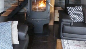 A cozy living room with a black wood-burning stove, a wooden staircase, and a sofa with patterned cushions. - Former sheepfold renovated with beautiful view of the Pyrenees ideal for the family (Astugue)