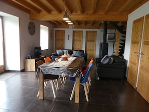 A dining area with a wooden table, chairs, and a black stove.