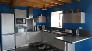A modern kitchen with stainless steel appliances, a blue accent wall, and a 'SALT' floor decal. - Former sheepfold renovated with beautiful view of the Pyrenees ideal for the family (Astugue)