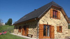 A stone house with a sloped roof, wooden shutters, and a small porch. - Former sheepfold renovated with beautiful view of the Pyrenees ideal for the family (Astugue)