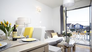 A modern hotel room with a sofa, dining table, and a view of the outside. - Beautiful, warmly decorated apartment-1st line sea-Pool (Biscarrosse)
