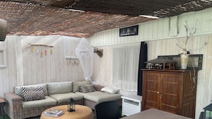 A cozy outdoor seating area with a wicker sofa, a round wicker ottoman, and a table with a tablecloth. - Peaceful haven with swimming pool near the port and beach (Audenge)