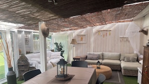 A cozy indoor space with a dining table, a sofa, and a cushioned seating area. - Peaceful haven with swimming pool near the port and beach (Audenge)