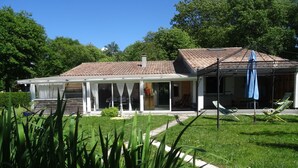 A two-story house with a covered patio area, a garden with a pathway, and outdoor seating. - Peaceful haven with swimming pool near the port and beach (Audenge)