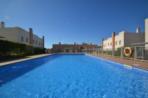A swimming pool with lifebuoys, surrounded by buildings with a clear sky above.