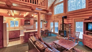 A log cabin interior with a kitchen, dining area, and living room.