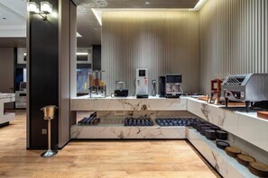 A modern hotel lobby with a marble reception desk, a coffee machine, and a seating area with a wooden floor. - Ningbo Nanyuan Zhaobaoshan Hotel (Ningbo)