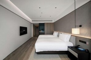 Ein modernes Hotelzimmer mit einem großen Bett, Nachttischen, einem Fernseher und einer Lampe.