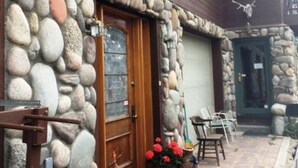 A stone facade with a wooden door, a stone wall with a rock pattern, a red sculpture, and a green planter with red flowers. -  Ski History Unit with 2 decks, sleeps 2- walk to Base area for concerts (Mt Crested Butte)