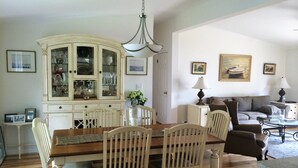 Een eethoek met een houten tafel en stoelen, een wit kastje met glazen deuren en een kroonluchter.