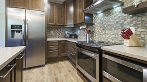 A modern kitchen with stainless steel appliances, wooden cabinets, and a tiled backsplash. - French Street Haven | 5 Minute Walk to Main Street (Breckenridge)