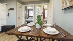 A dining area with a wooden table set for four, white plates, and a vase with a white orchid. - French Street Haven | 5 Minute Walk to Main Street (Breckenridge)