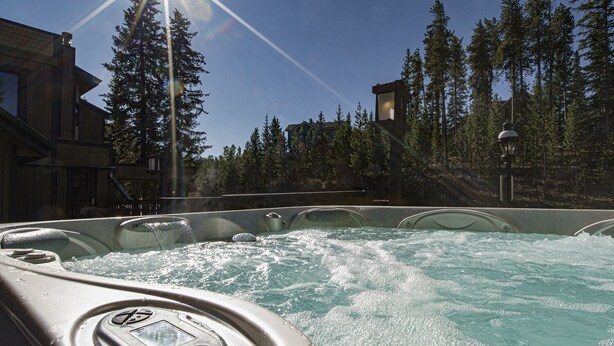A hot tub area with a clear view of the surrounding forest and a building with a hexagonal roof. - French Street Haven | 5 Minute Walk to Main Street (Breckenridge)