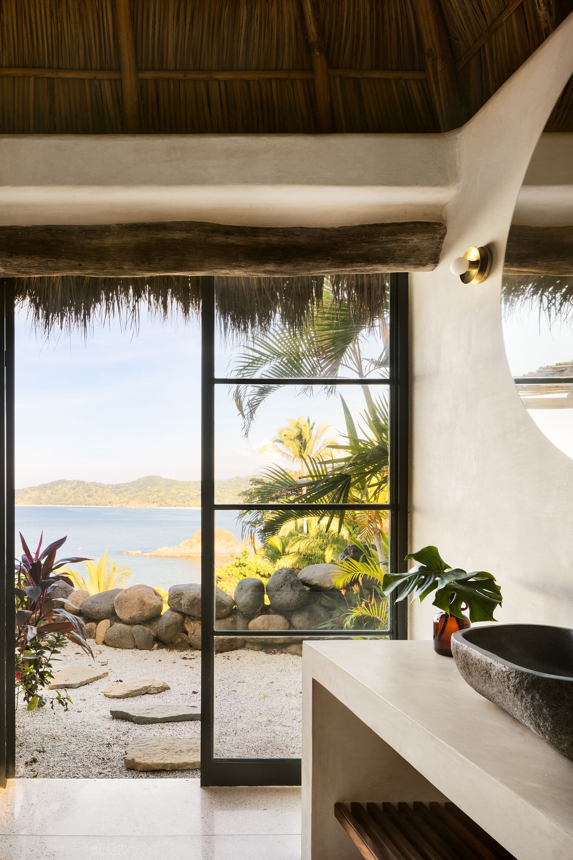 A modern interior with a large window offering a view of a beach and palm trees.