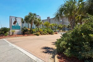 A paved walkway leading to a building with a sign reading "Navarre Beach Regency."