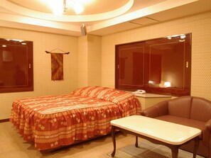 Classic hotel room with a double bed, small table, and leather armchair.