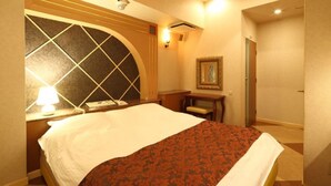 A hotel room with a bed, a desk, a lamp, and a framed picture on the wall. - Fine Sakai (Sakai)