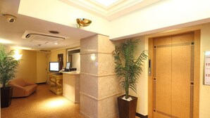 A hotel lobby with a reception desk, a computer, a plant, and an elevator. - Fine Sakai (Sakai)