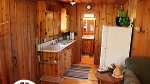 A compact wooden cabin with a kitchenette, a dining area, and a living space. - Private log cabin with view overlooking Grand Lake (Presque Isle)