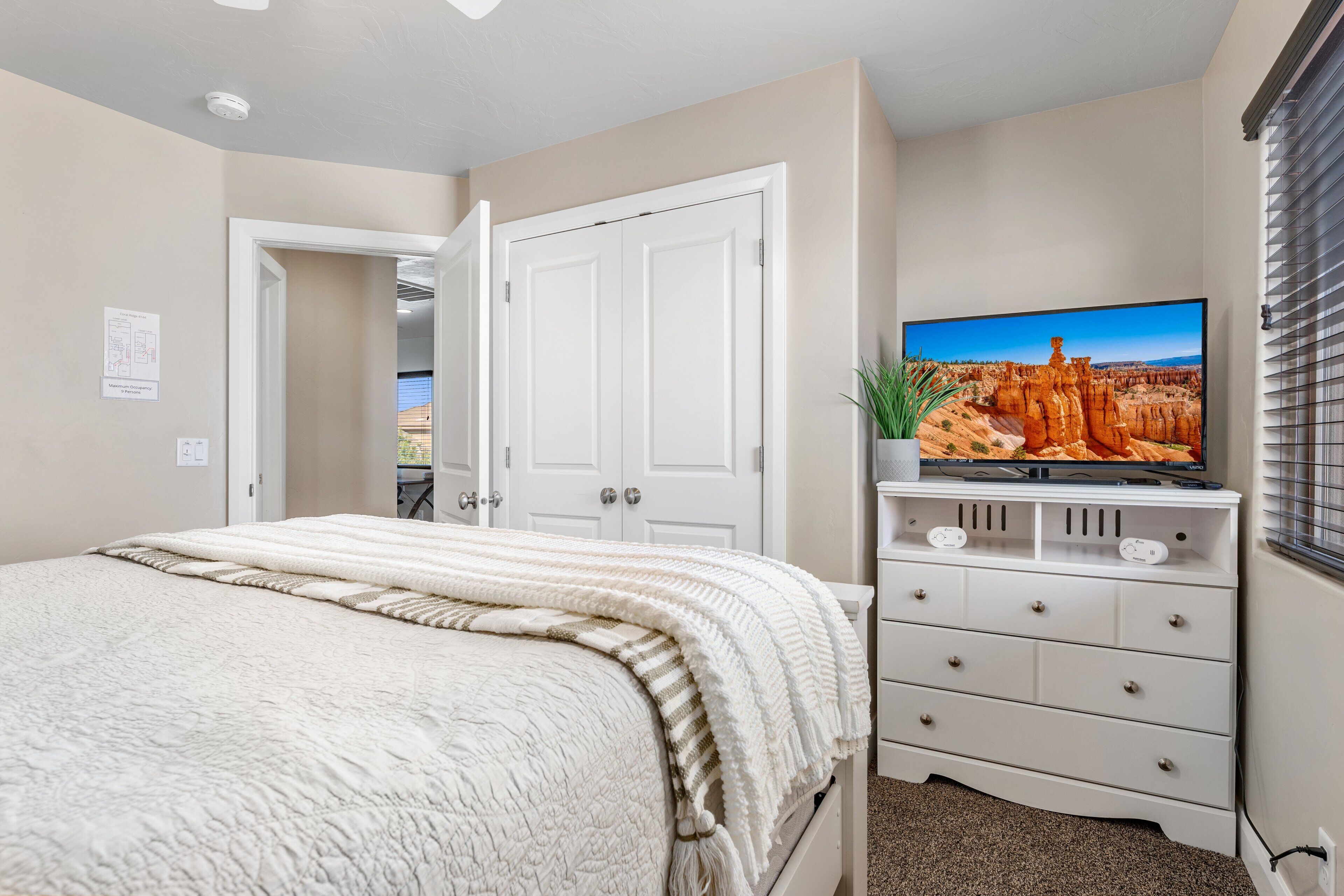 Un dormitorio con una cama grande, un televisor sobre una cómoda y una puerta que da a otra habitación.