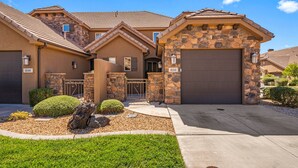 A two-story house with a stone facade, a garage, and a well-maintained front yard with a rock feature and trimmed bushes. - Coral Ridge 4144, Hot Tub, Bikes, Scooters, and near Coral Canyon Golf Course, SLP 12 (Washington)