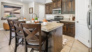 A kitchen with dark wooden cabinets, a granite countertop, and a central island with seating. - Coral Ridge 4144, Hot Tub, Bikes, Scooters, and near Coral Canyon Golf Course, SLP 12 (Washington)