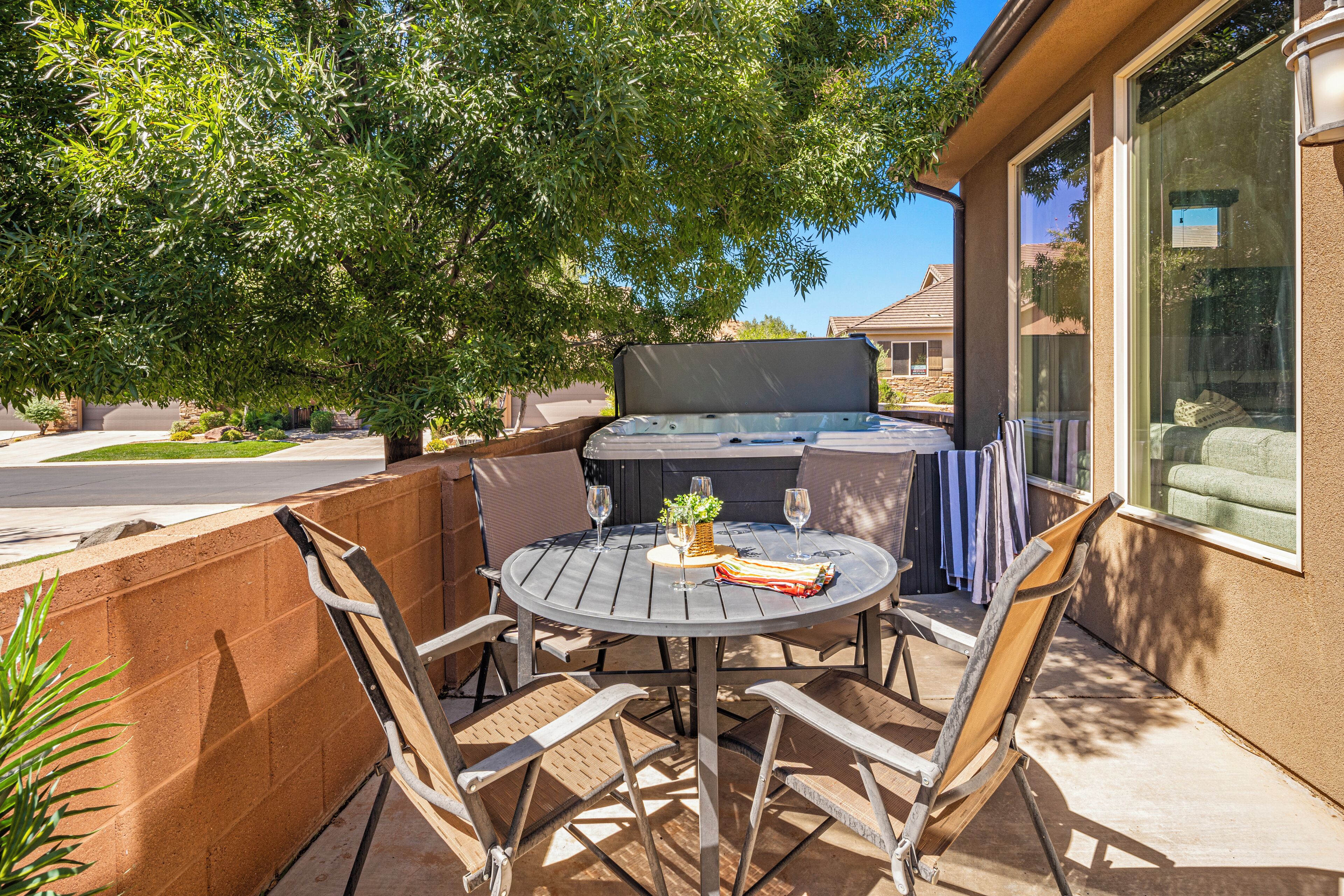 An outdoor patio with a round table, chairs, and a barbecue grill.