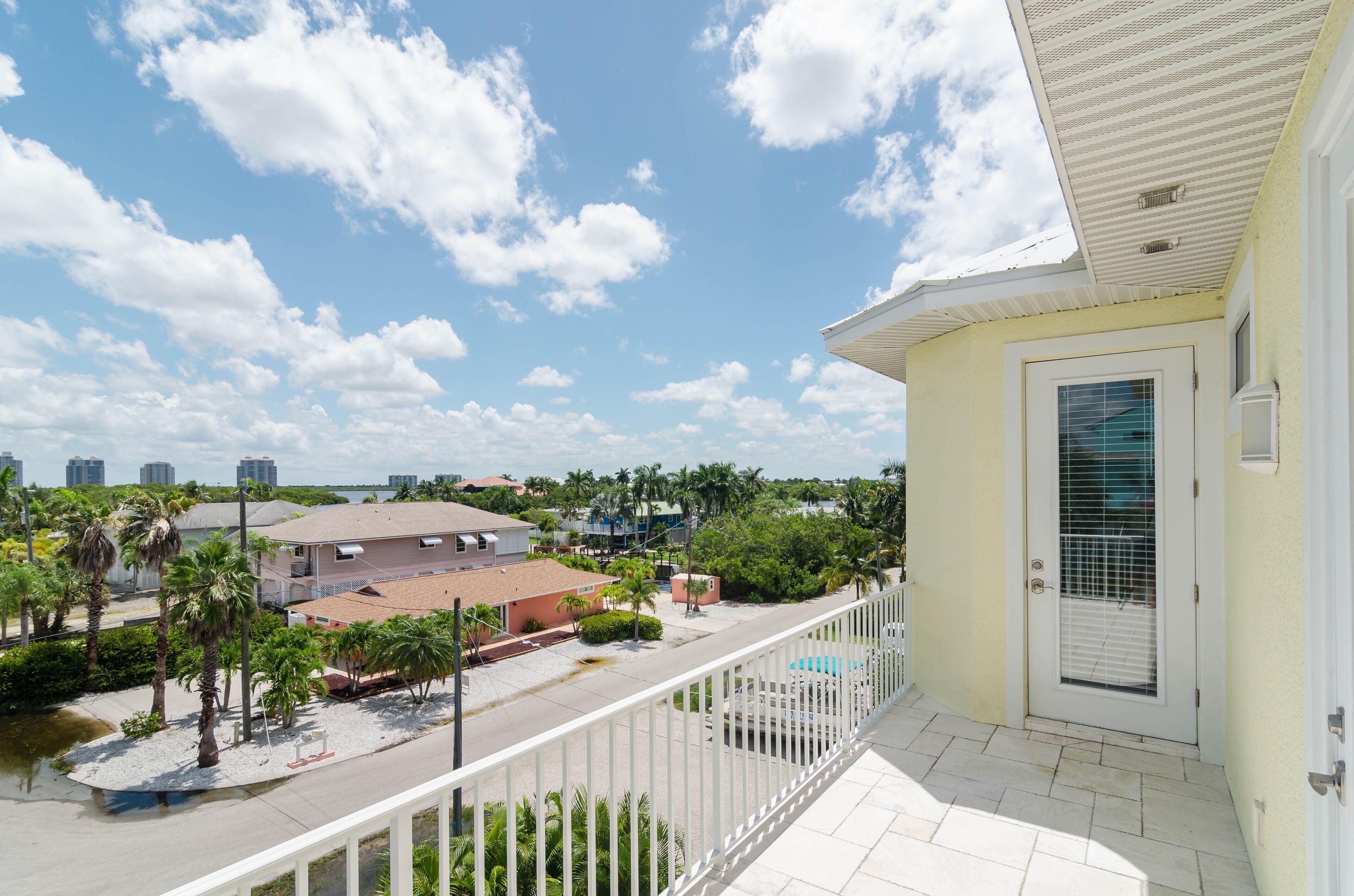 A balcony with a view of a residential area, including houses and palm trees.