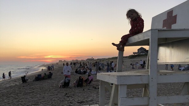 A beach scene with a lifeguard tower and people in the background.