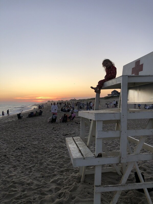 Une scène de plage avec une tour de surveillance et des personnes en arrière-plan.