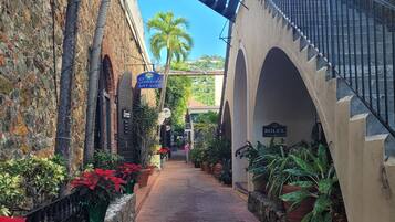 A brick pathway flanked by stone walls and potted plants, leading to a building with a sign for 'Seaside Gift Shop'.