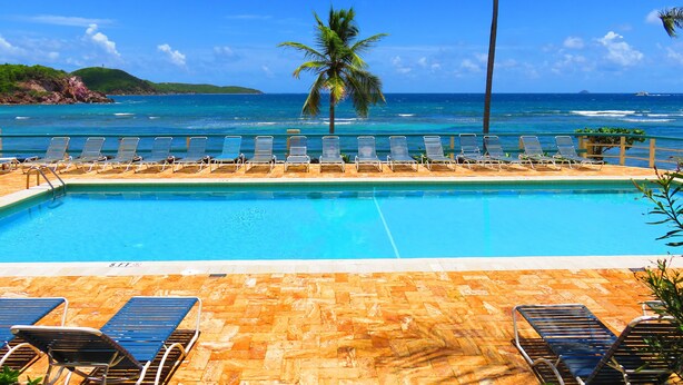 A pool with lounge chairs and a view of the ocean. - REMODELED 2026! Prime OCEANFRONT POOLSIDE 2BR/2BA Condo-BEST location+Generator (St Thomas)