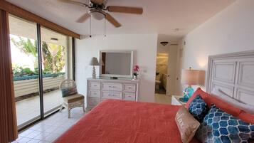 A bedroom with a bed, a dresser, a mirror, a ceiling fan, and a view of the outside.