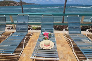 A row of blue lounge chairs with a hat and a colorful bag on the table. - REMODELED 2026! Prime OCEANFRONT POOLSIDE 2BR/2BA Condo-BEST location+Generator (St Thomas)