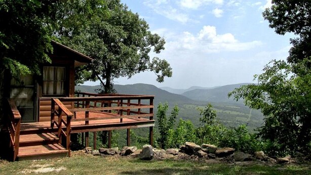 Eine Holzhütte mit einer Terrasse mit Blick auf eine Berglandschaft.