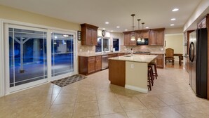 A spacious kitchen with a large island, wooden cabinets, and a refrigerator. - Family Fun, Pickleball, Pool/Spa, Water slide (Las Vegas)