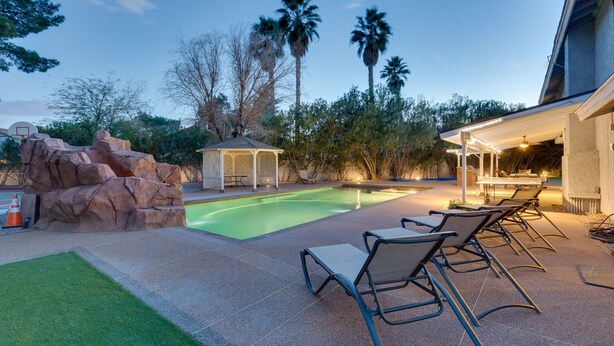 A swimming pool with lounge chairs, a gazebo, and palm trees. - Family Fun, Pickleball, Pool/Spa, Water slide (Las Vegas)
