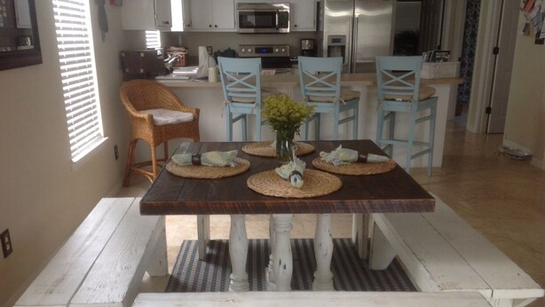 Un espace repas avec une table en bois et des bancs blancs, entouré de chaises bleu clair.