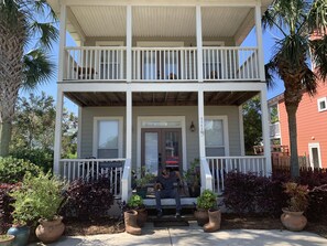 A two-story house with a porch, a dog, and a child playing nearby.