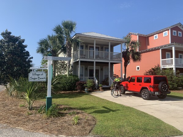 A two-story building with a balcony, a red vehicle parked in front, and a sign indicating 'Village of Sugar Beach.'