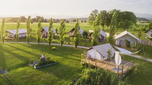 A series of tents in a grassy field with a clear sky. - Glamping Kolpa Resort (Metlika)