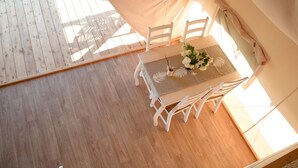 A wooden floor, a table with chairs, and a tent-like structure. - Glamping Kolpa Resort (Metlika)