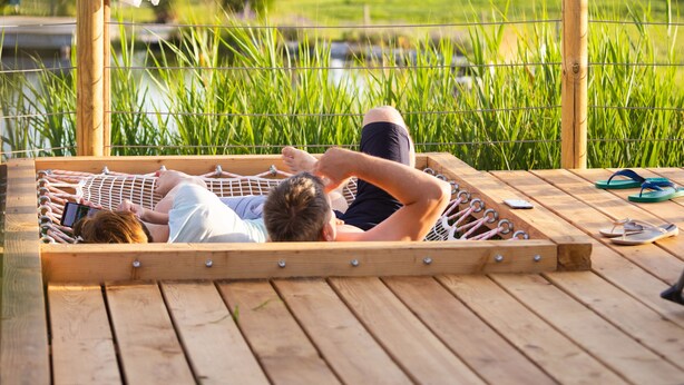 A wooden deck with a hammock and a wooden pergola with a white canopy. - Glamping Kolpa Resort (Metlika)