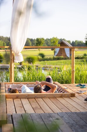 A wooden deck with a hammock and a wooden pergola with a white canopy. - Glamping Kolpa Resort (Metlika)