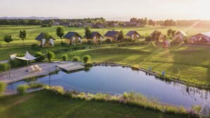 A serene lakeside property with multiple cabins, a dock, and a well-maintained lawn. - Glamping Kolpa Resort (Metlika)